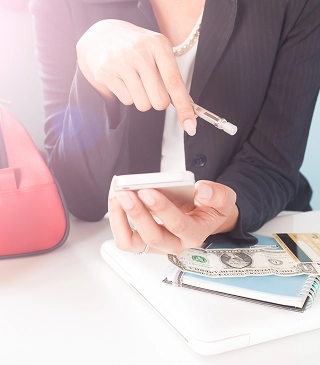 A Woman Holding A Cell Phone In One Hand And A Purse In The Other
